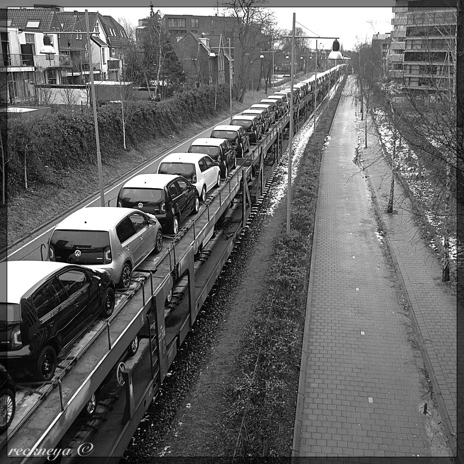 This photo was taken from a bridge near the train station of Amersfoort. This train is going to the PON dealership on the other end of the track, several kilometres away, in Leusden. The train track is perhaps the oldest in Amersfoort. It is a single track, with no electricity cables running above it. The locomotive pulling these wagons is a strong diesel. Except for the weekends a train like this, easily hundreds of meters long, goes to the dealership and returns that same day empty.
